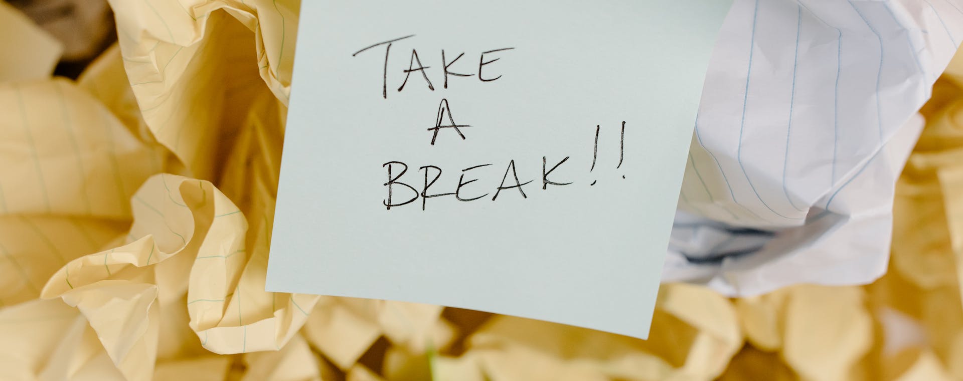 Sticky note with 'Take a Break' on crumpled paper background.