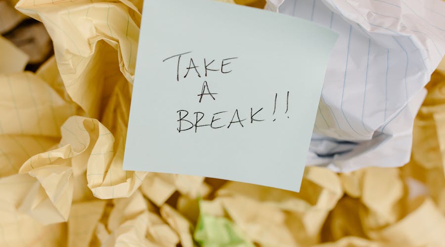 Sticky note with 'Take a Break' on crumpled paper background.