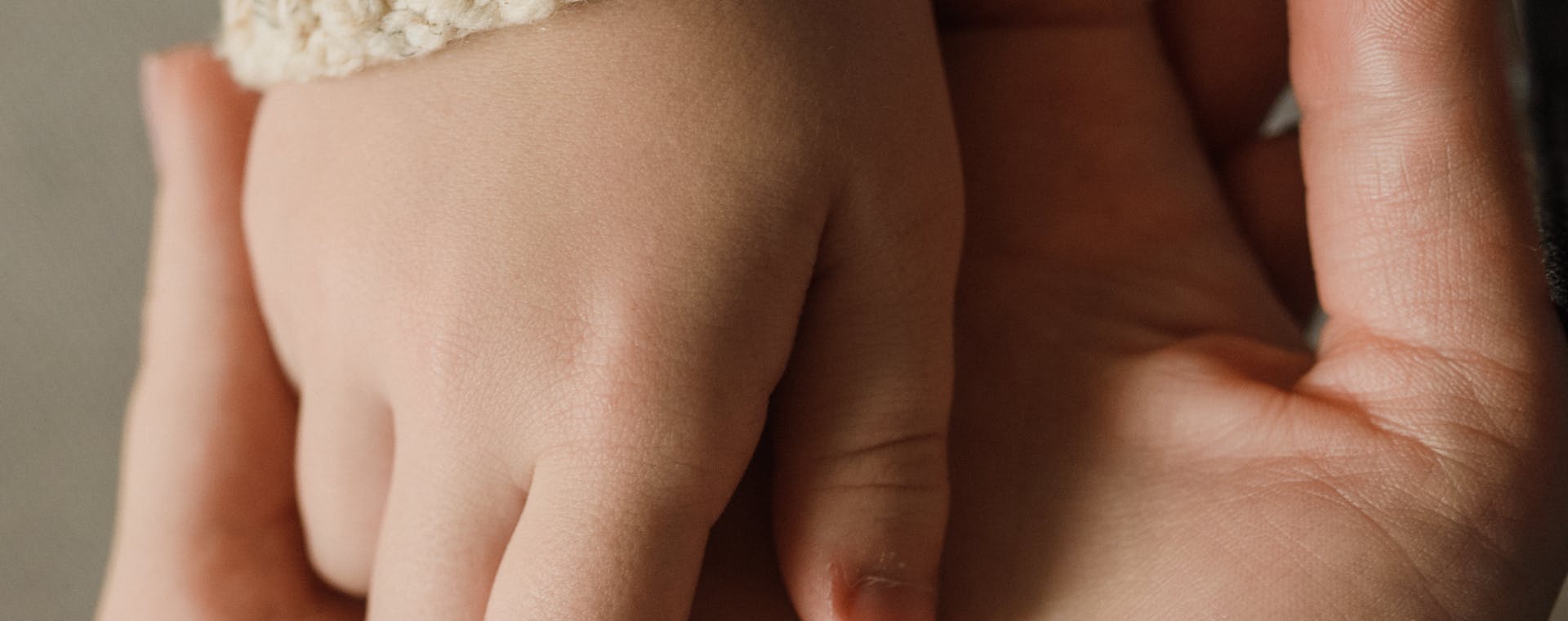 Intimate close-up of a child and adult holding hands, showing warmth and care.