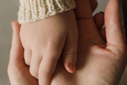 Intimate close-up of a child and adult holding hands, showing warmth and care.