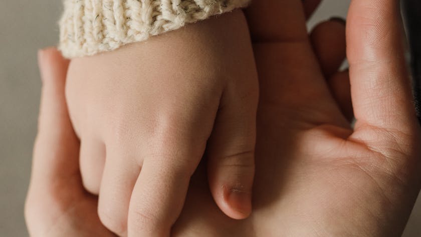 Intimate close-up of a child and adult holding hands, showing warmth and care.