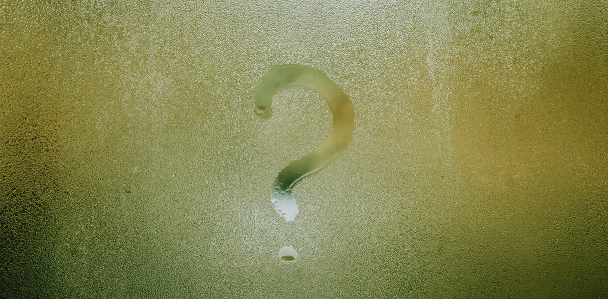 A question mark drawn on foggy glass, evoking curiosity and mystery.