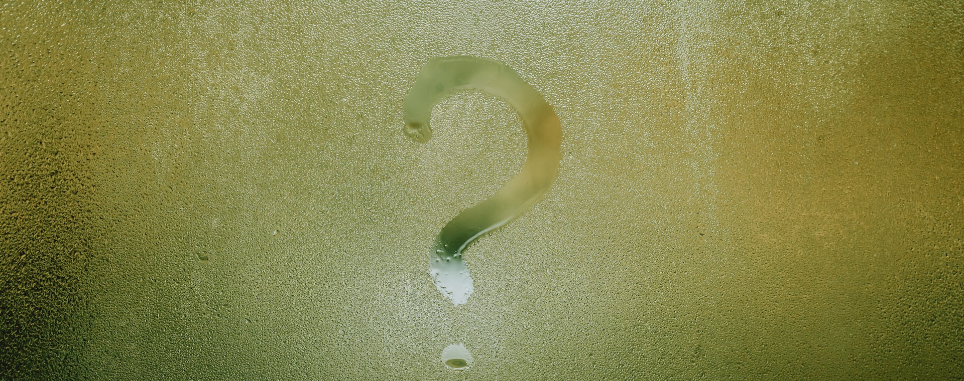 A question mark drawn on foggy glass, evoking curiosity and mystery.