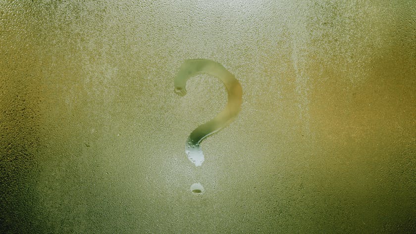 A question mark drawn on foggy glass, evoking curiosity and mystery.