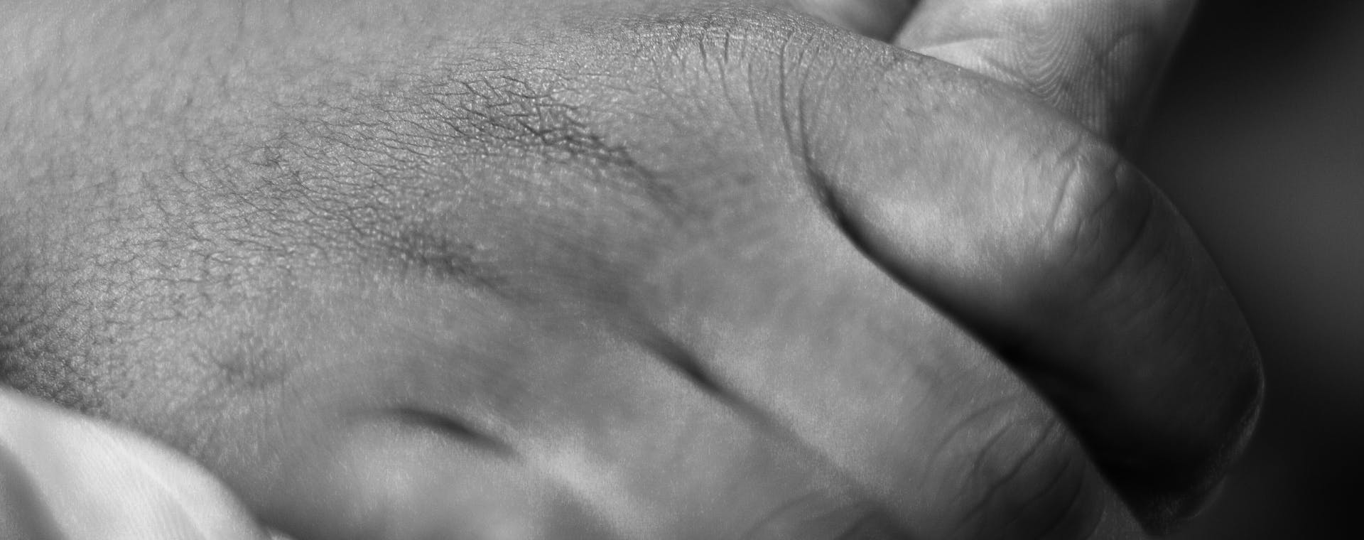 Close-up black and white photo of a child's hand holding an adult's, symbolizing care and connection.