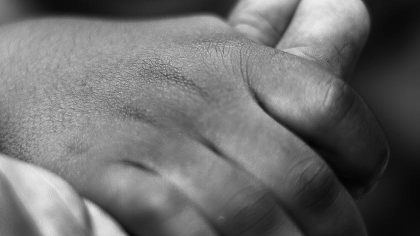 Close-up black and white photo of a child's hand holding an adult's, symbolizing care and connection.